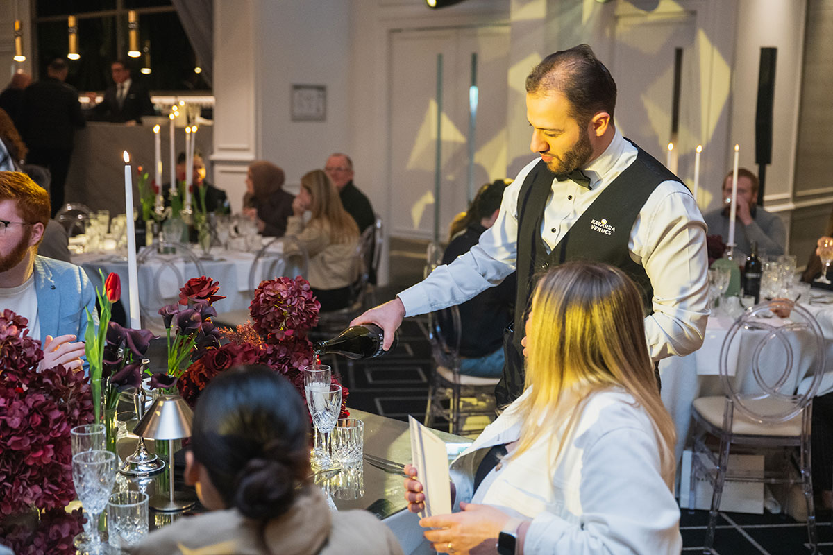 Waiter pouring drinks at The Art of Hopitality Menu Tasting