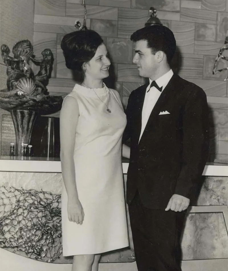 Black and white photograph of Filippo and Sarina Navarra smiling at each other in formal attire.