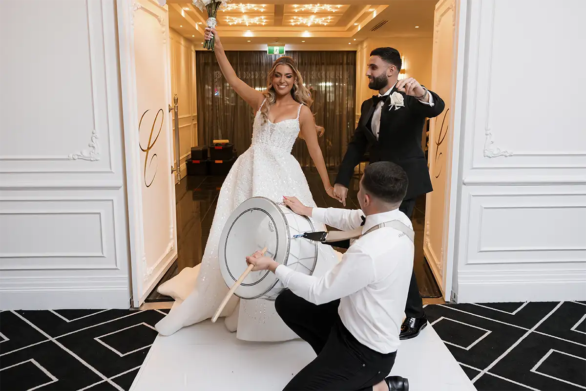 Bride and groom entering their wedding reception with a drummer at Conca D'oro